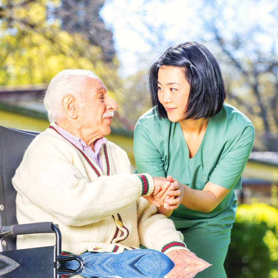 an elderly man holding the hands of a caregiver woman