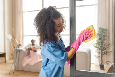 caregiver cleaning. curly african-american caregiver cleaning the glass door at home of the patient