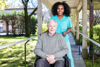 african nurse helping man on the wheelchair.