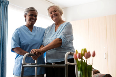 Portrait of nurse standing by senior women holding walker in nursing home